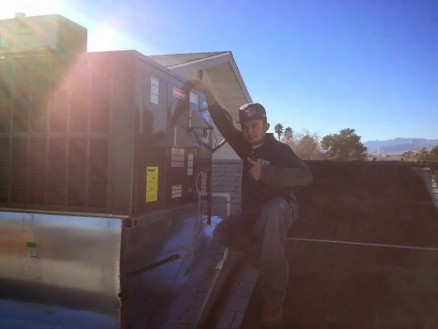 HVAC technician performing HVAC Inspection on a rooftop unit in Clive
